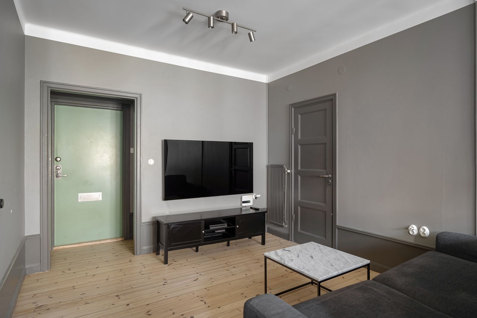 Small living room with a flat-screen TV mounted on the wall above a black media console